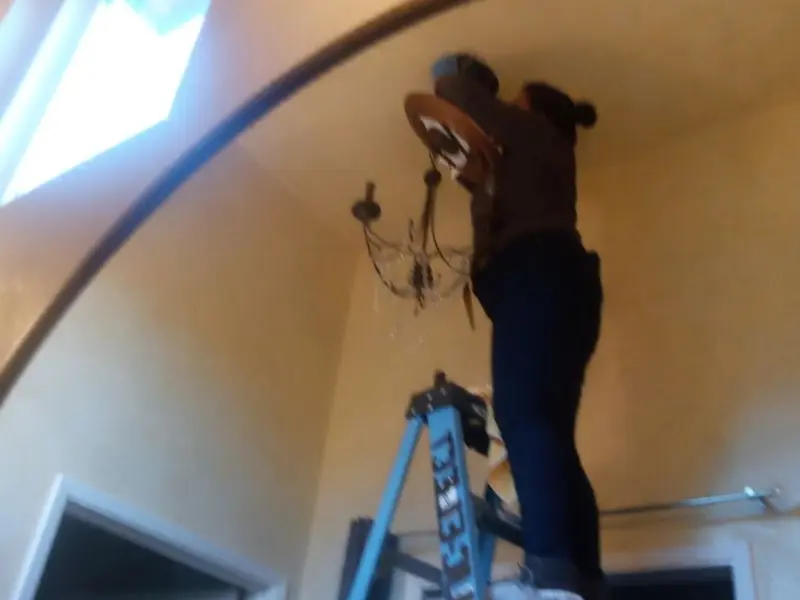 Electrician installing a chandelier in a South Sarasota residence